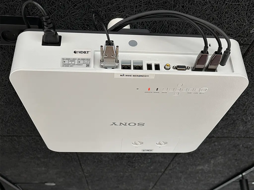 En hvid Sony projektor der er monteret på et sort loft