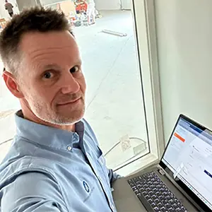 Ejer af Passion for AV Henrik Tovgaard stå foran en computer in en blå skjorte