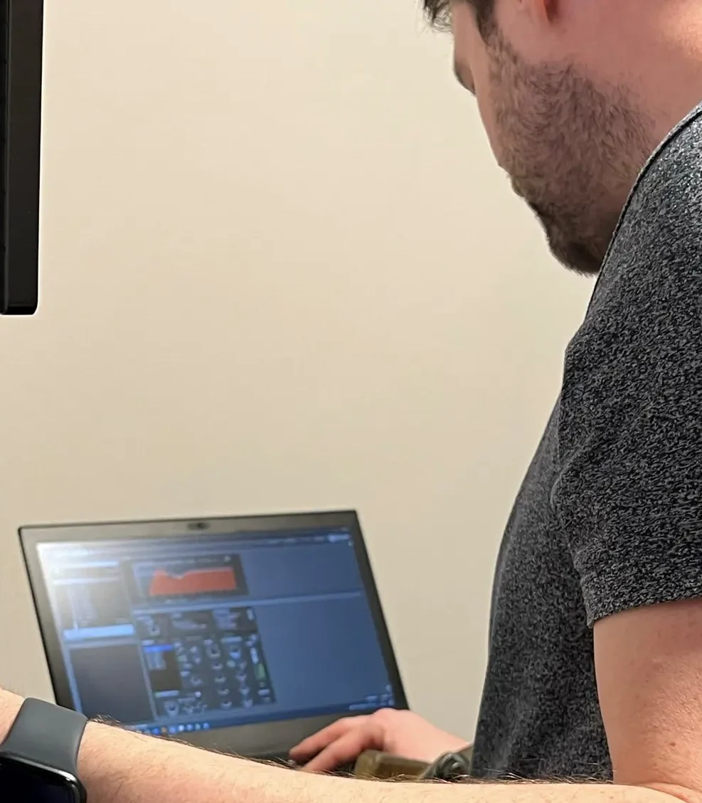 En mand står foran en computer og programmere et lydsystem